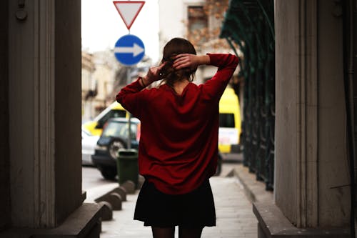 免费 红色的毛衣和黑色的超短裙，抱着头发的女人面对路 素材图片