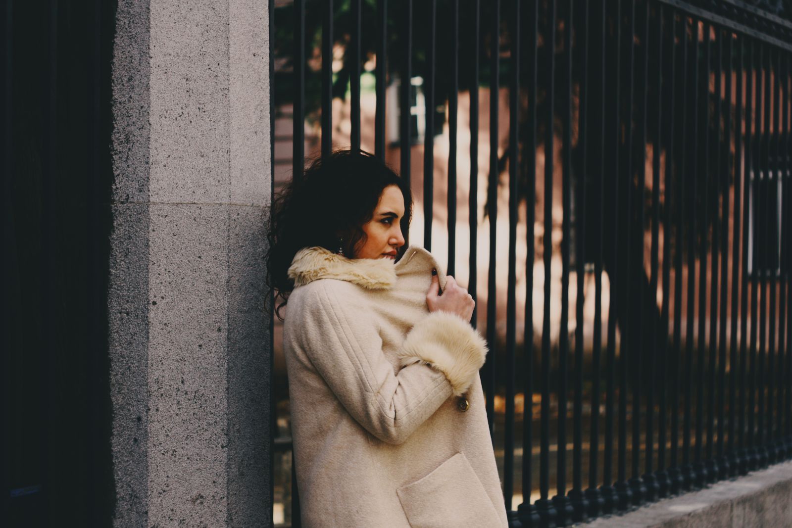Woman in beige coat against iron fence