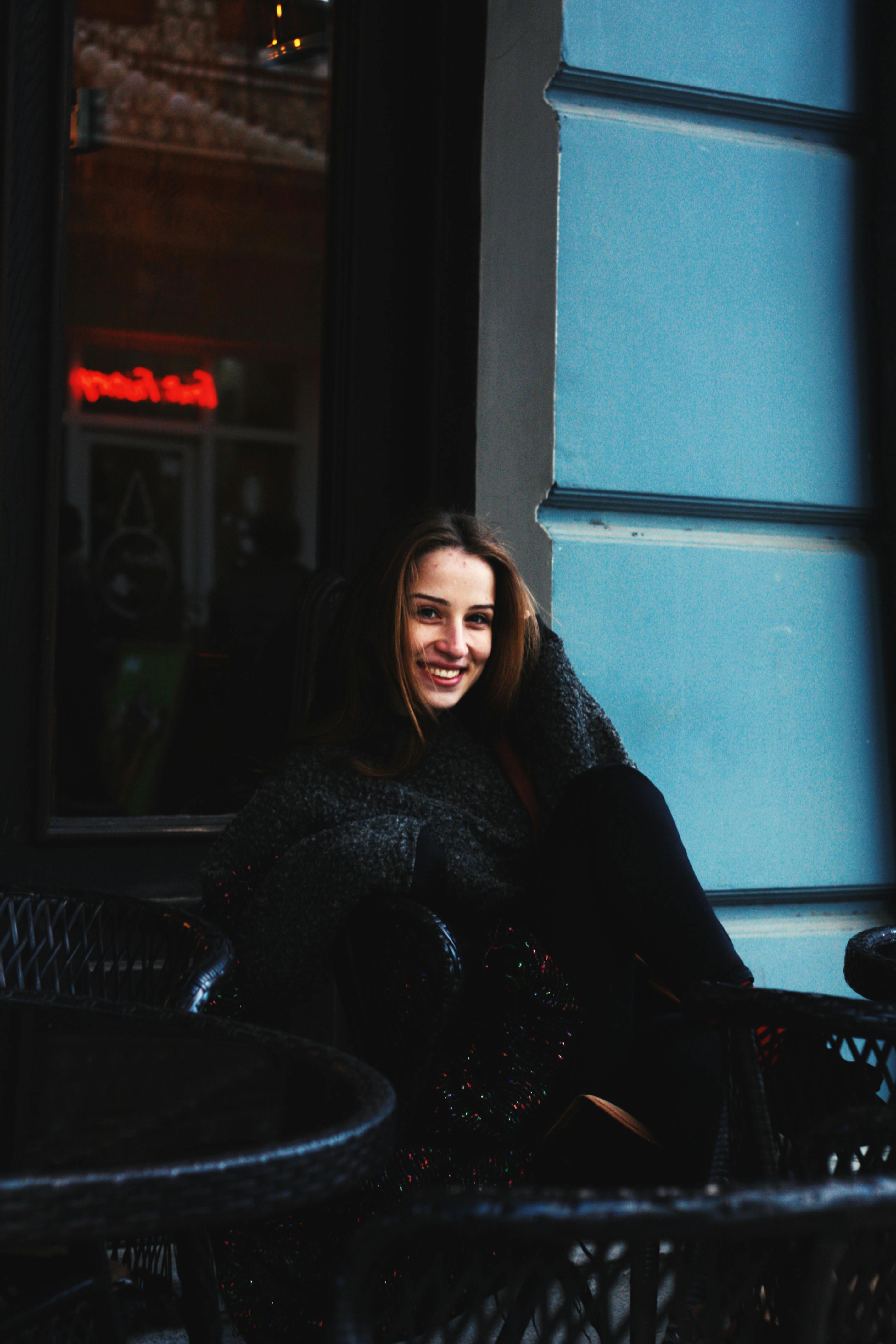 一名年轻女子坐在咖啡馆窗前，微笑着享受这舒适的时刻