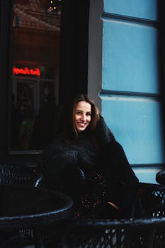 一名年轻女子坐在咖啡馆窗前，微笑着享受这舒适的时刻