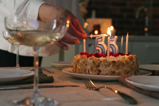 A close-up of a cake with candles celebrating a 55th birthday, set in a cozy indoor setting.