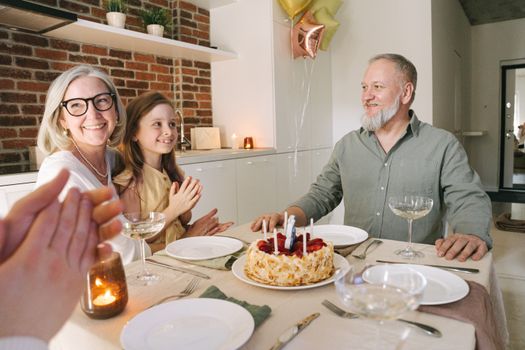 Happy family enjoying a birthday celebration with a cake and candles indoors.