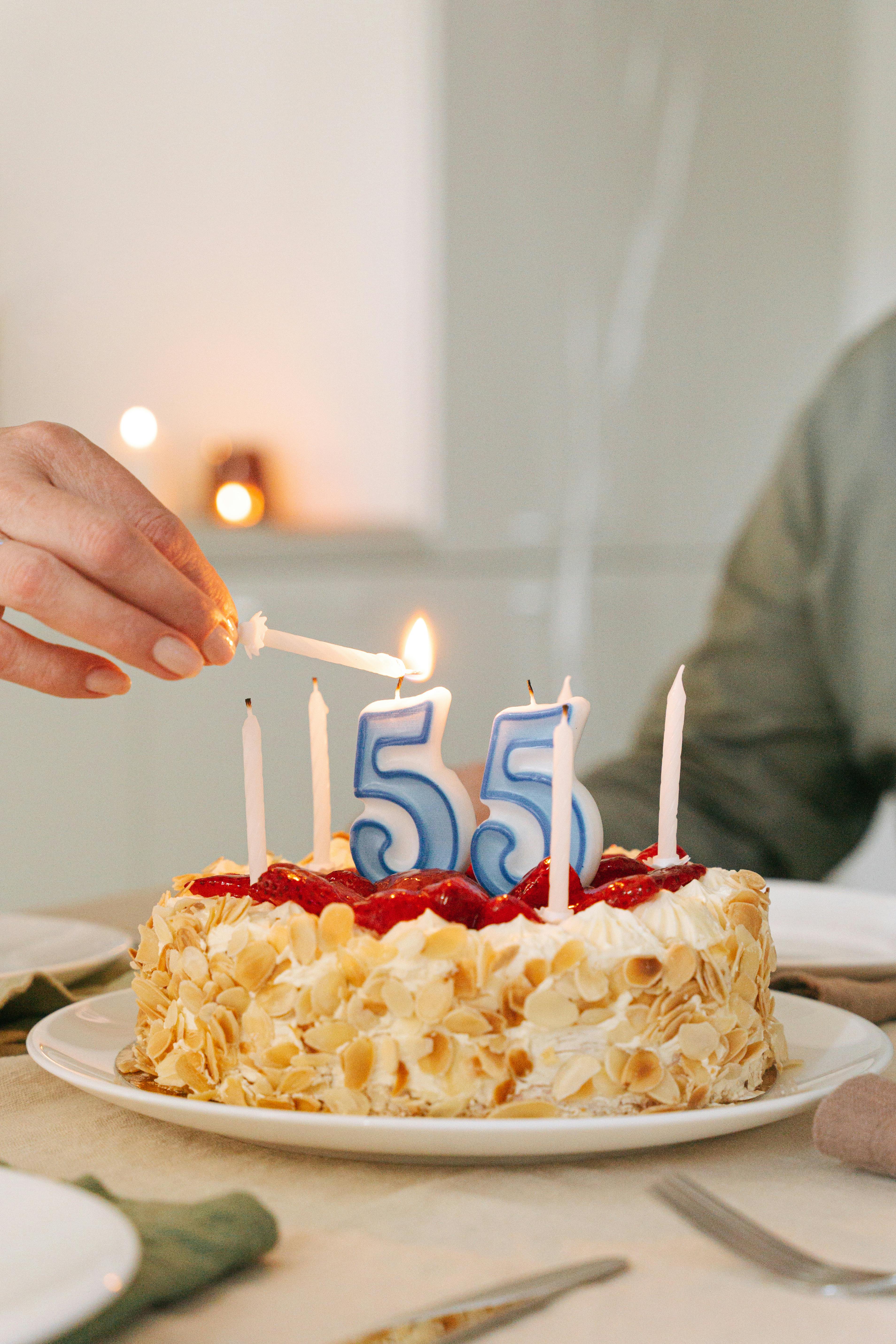 A delicious 55th birthday cake adorned with candles and almonds, ready for celebration.
