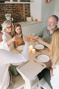 A family of five toasting with champagne glasses at a cozy dinner table with candles.
