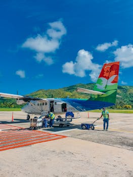 Colorful aircraft with workers on tarmac at Seychelles airport beneath clear blue sky.