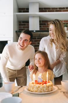 Family celebration with a birthday cake featuring lit candles and a joyful atmosphere.