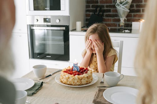 Free A Girl Covering Her Eyes Near a Birthday Cake Stock Photo