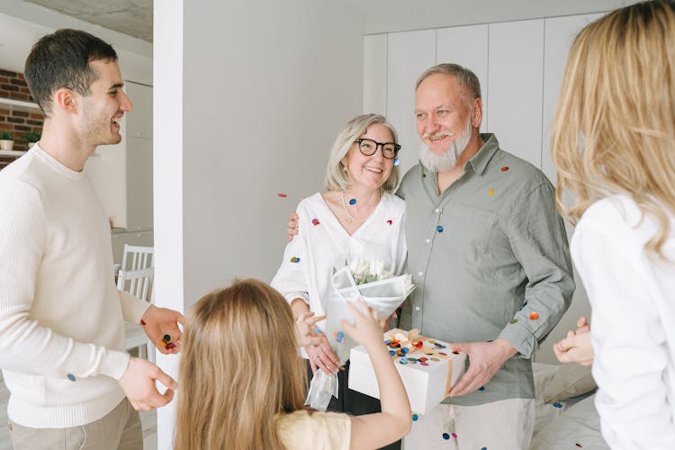 Senior Couple Holding A Gift Box And Bouquet Of Flowers