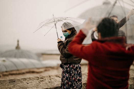 Woman wearing face mask and holding transparent umbrella on a rainy city landscape.