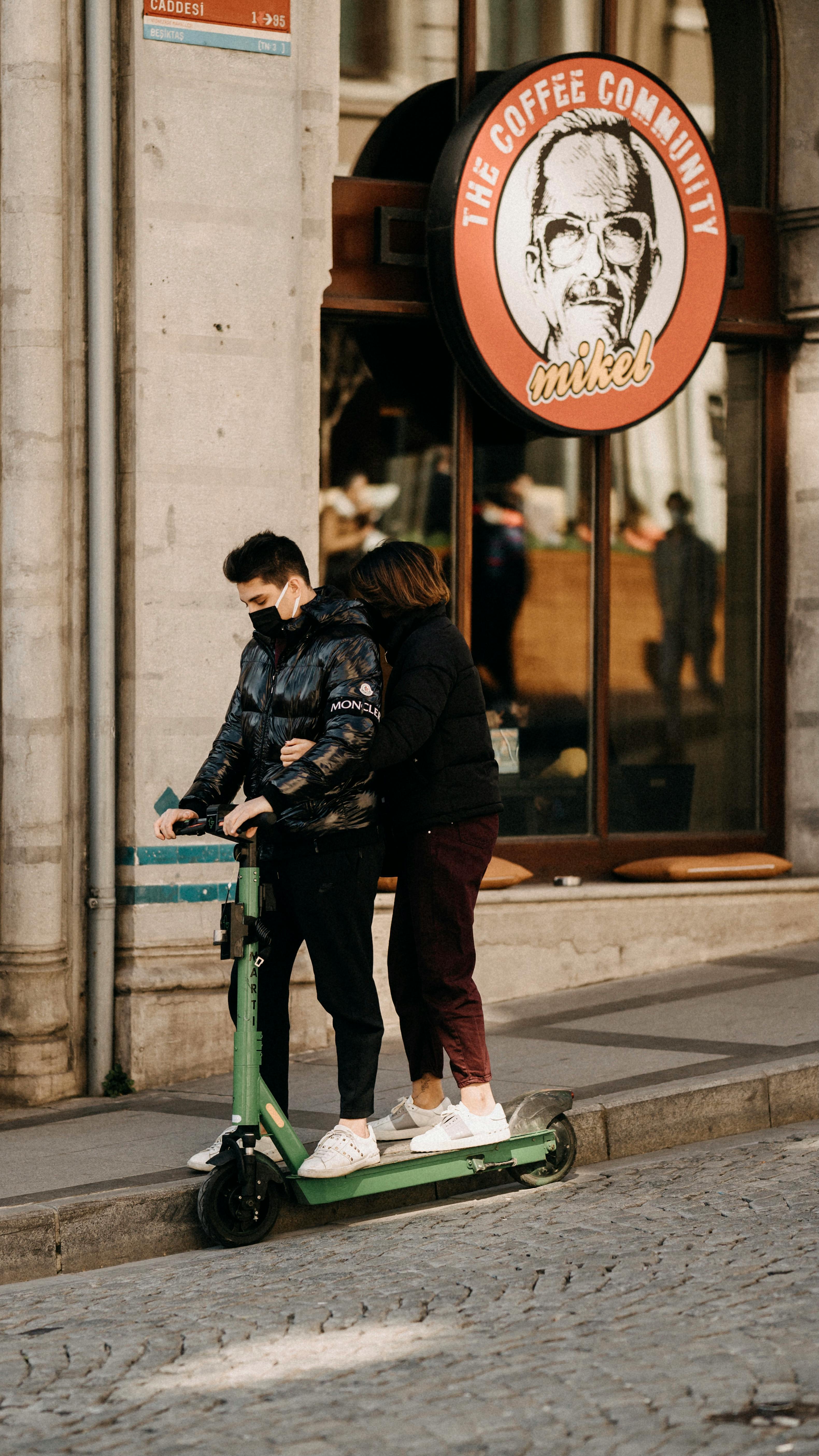 a couple riding an electronic scooter on a sidewalk