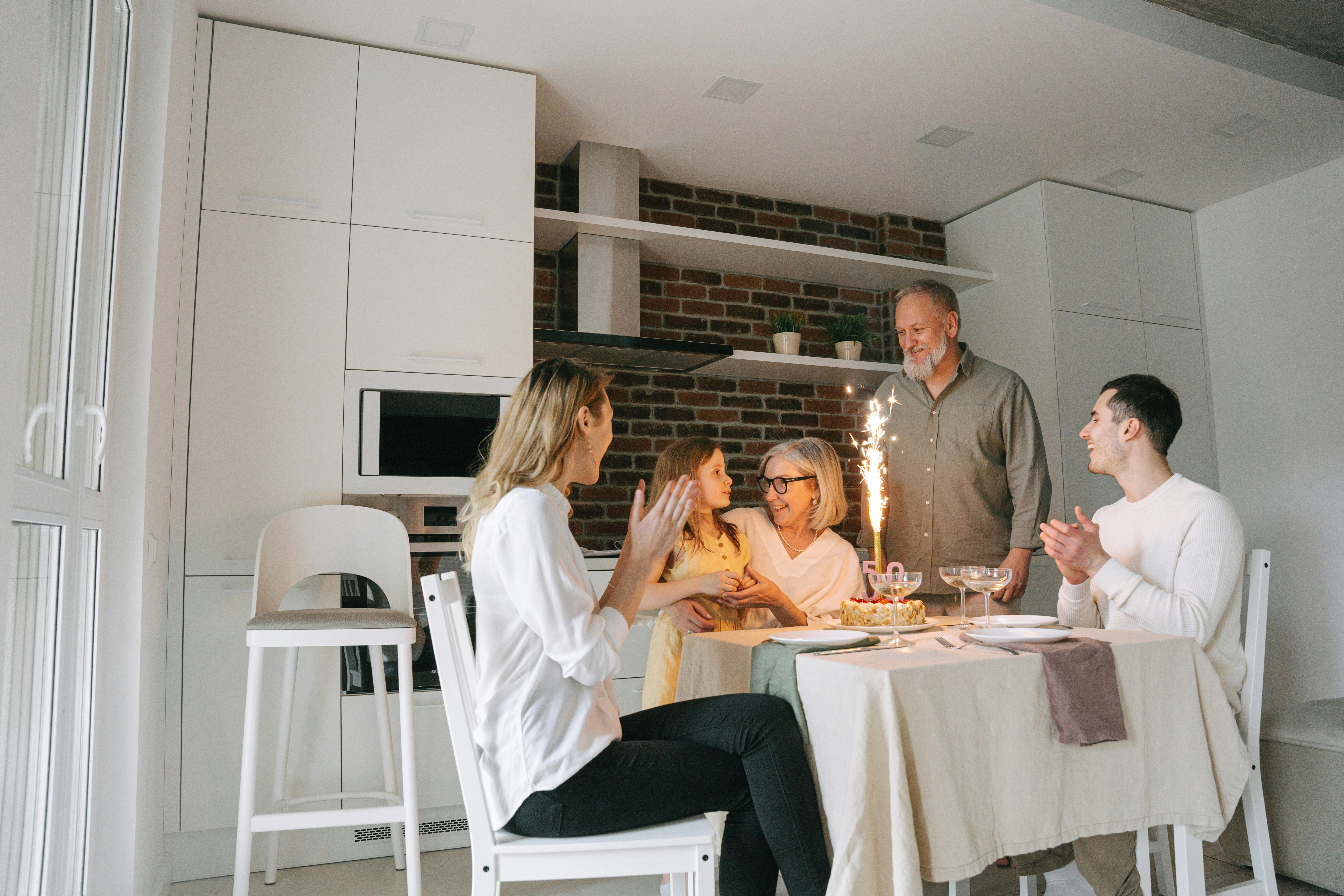 Joyful family gathering celebrating a birthday with a cake and sparkling candle in a cozy dining room.