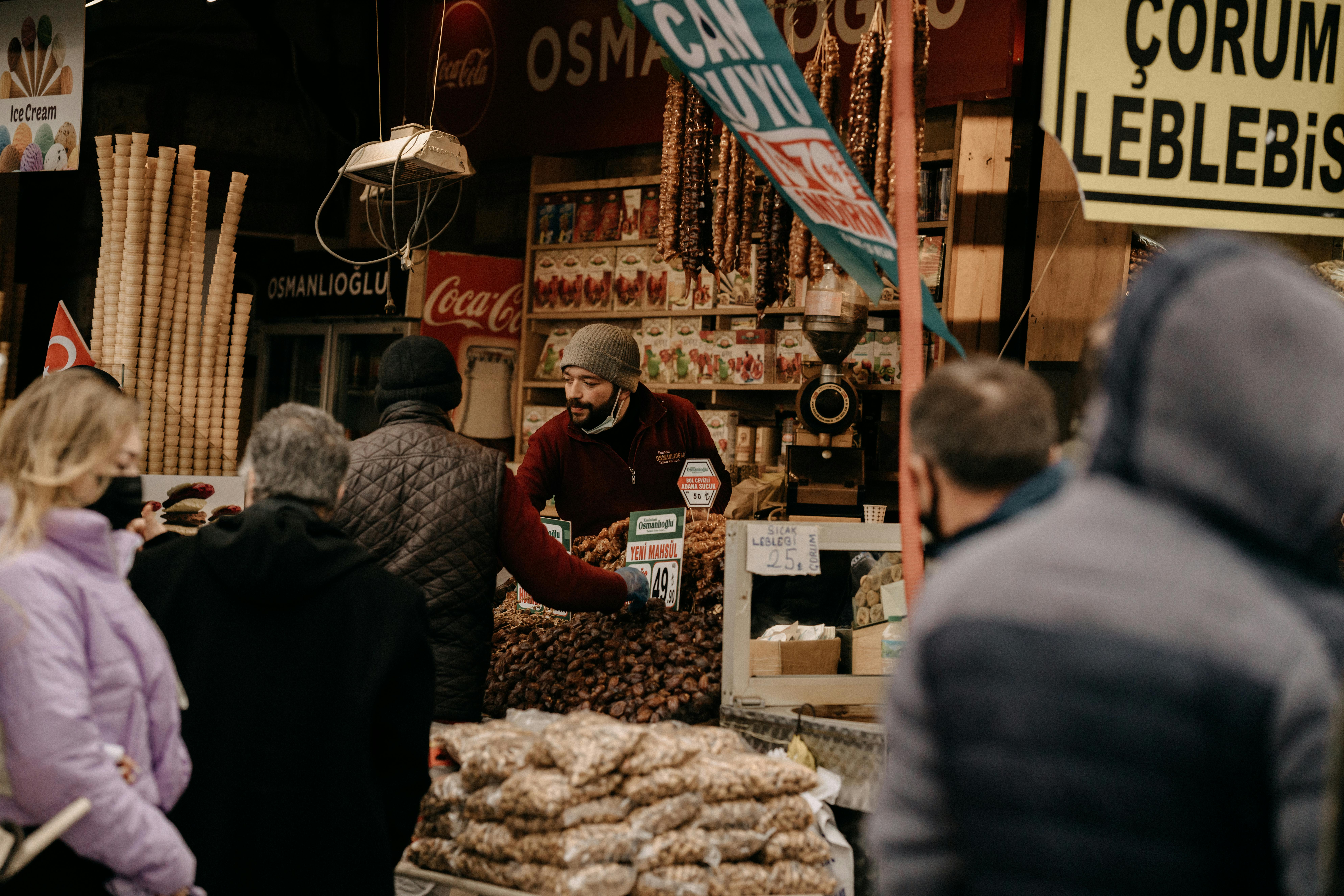 An engaging scene of a vendor in a beanie at a busy market stall with customers.