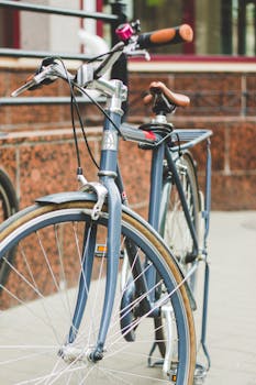A vintage bicycle with a leather saddle parked by a brown tiled wall in an urban setting.