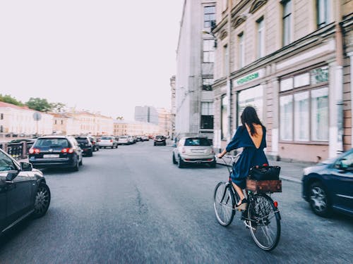 Woman Riding a Bicycle Between Parked Cars