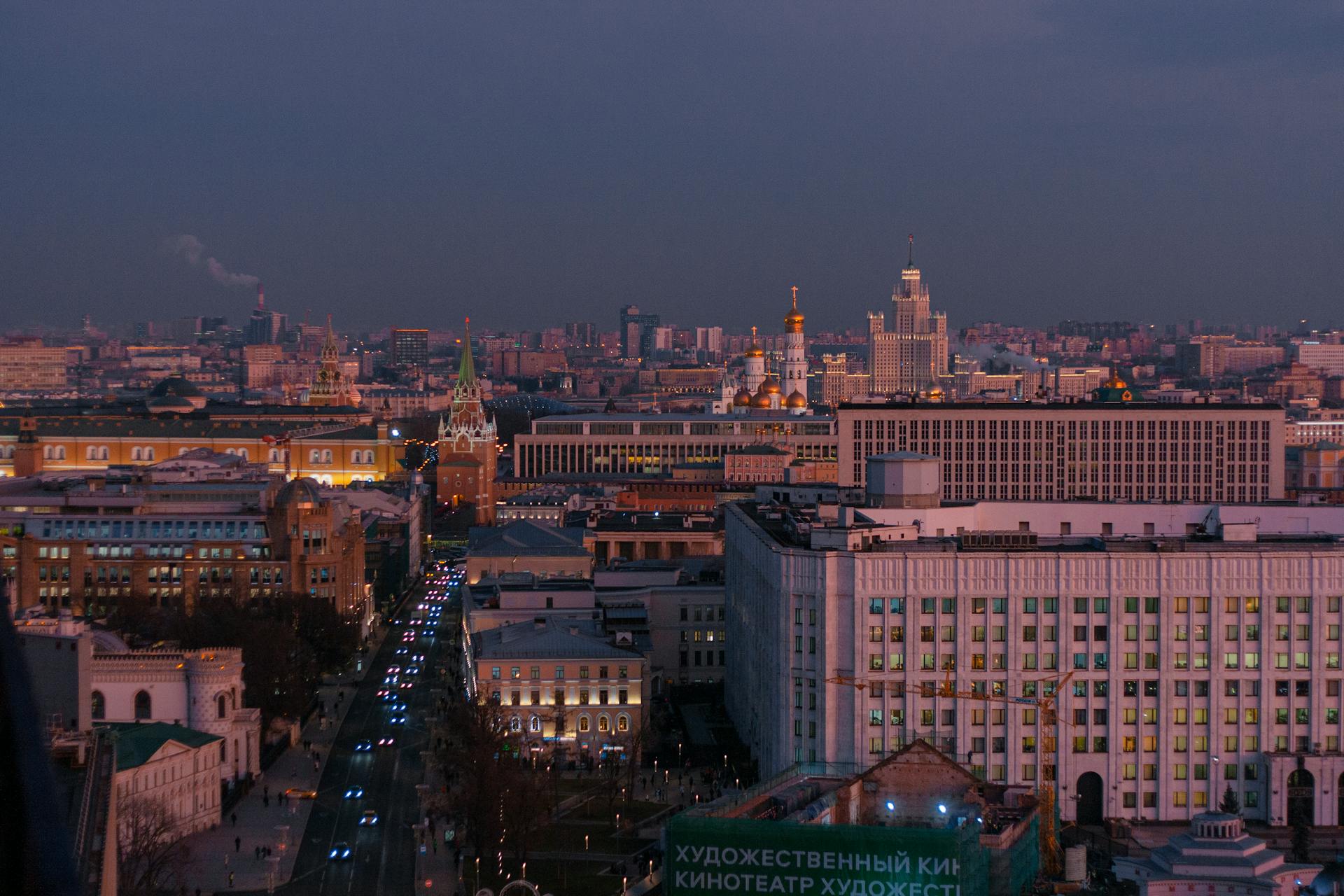 A stunning aerial view of Moscow cityscape during twilight, featuring the illuminated Kremlin and bustling streets.