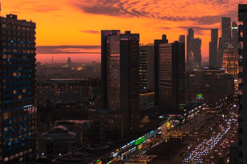 Free A breathtaking view of Moscow's skyline with skyscrapers and an orange sky at sunset. Stock Photo