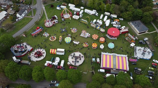 Aerial shot depicting colorful amusement park rides and stalls in Houghton Regis, England.