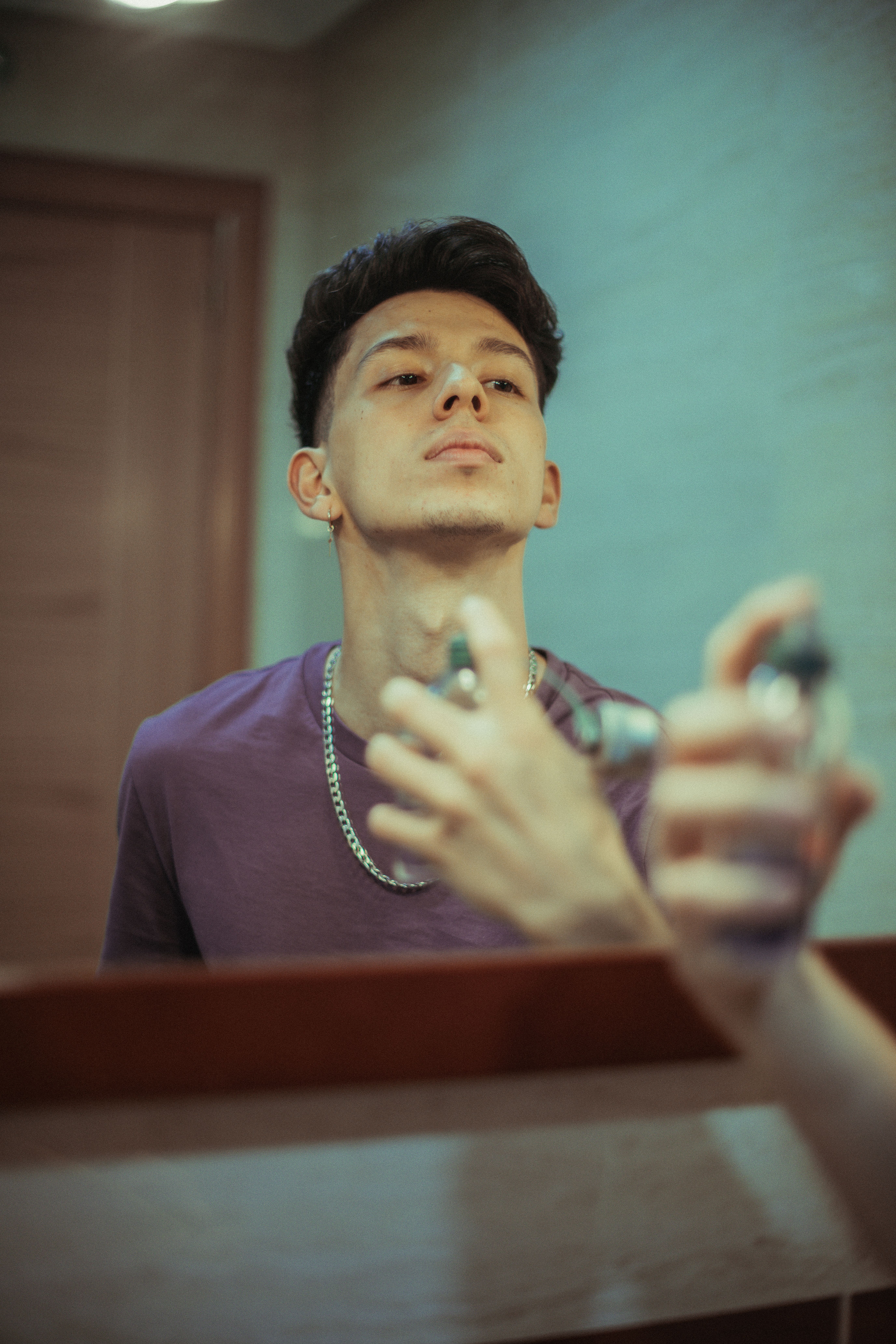 man applying cologne to neck pulse point before going out grooming