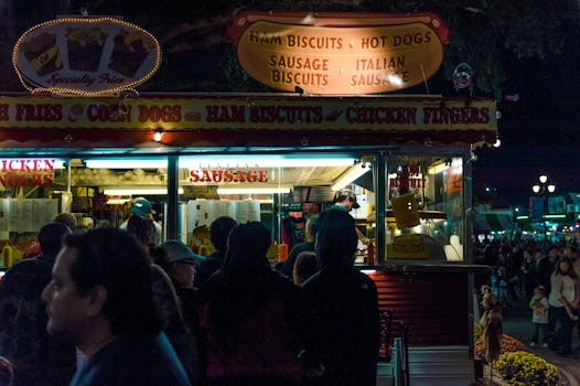 A bustling street food booth in Raleigh at night, offering snacks to a crowd.