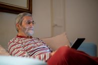 Man in Red White and Black Stripe Polo Shirt Sitting on Red Sofa