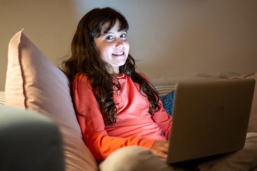 Free Smiling girl enjoying time on a laptop indoors, cozy home setting. Stock Photo