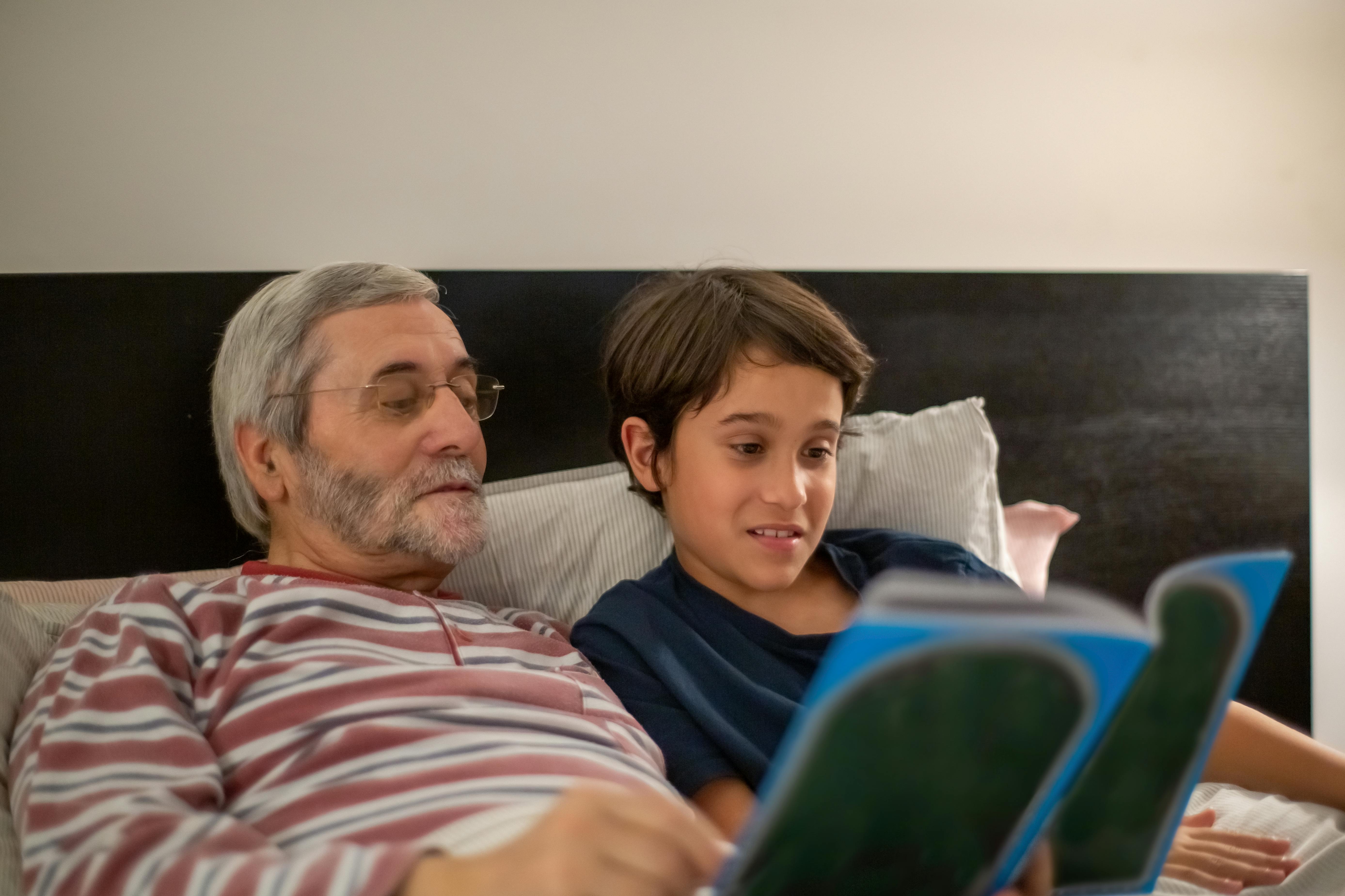 man reading a book with his grandson