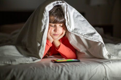 Photo of a Girl in a Red Shirt Watching on Her Smartphone