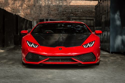 Free Front view of a luxury red sports car parked in an urban setting. Sleek and modern design. Stock Photo