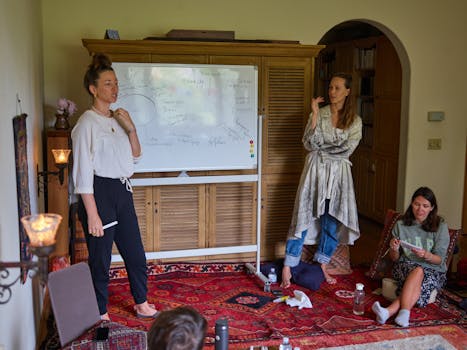 A group of adults in a cozy room participating in a casual meeting with a whiteboard.