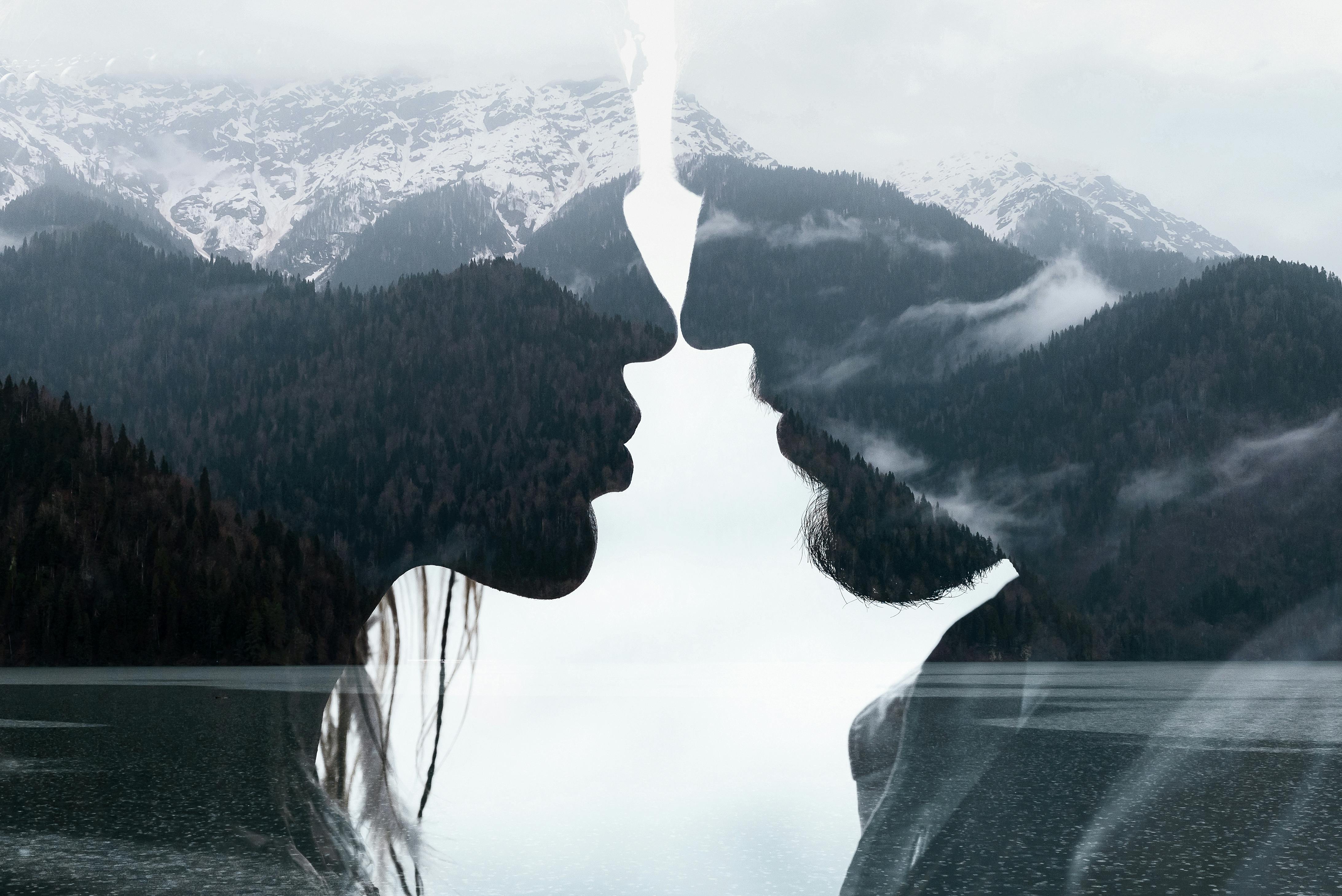 woman and man silhouette profiles with mountain landscape overlaid