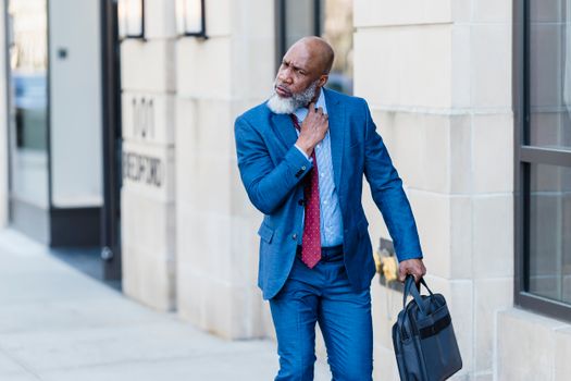 Serious black businessman walking on street