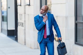 Serious black businessman walking on street