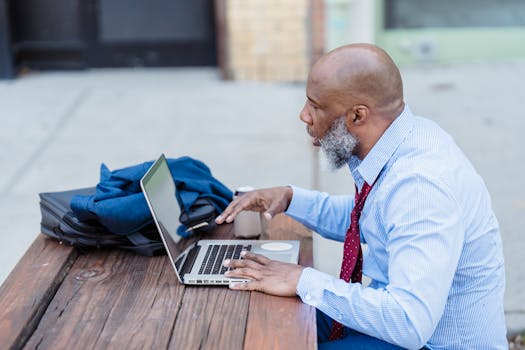 Side view of an African American businessman using a laptop at an outdoor workspace.