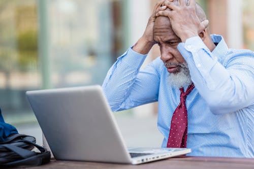 Stressed beard black man working on laptop