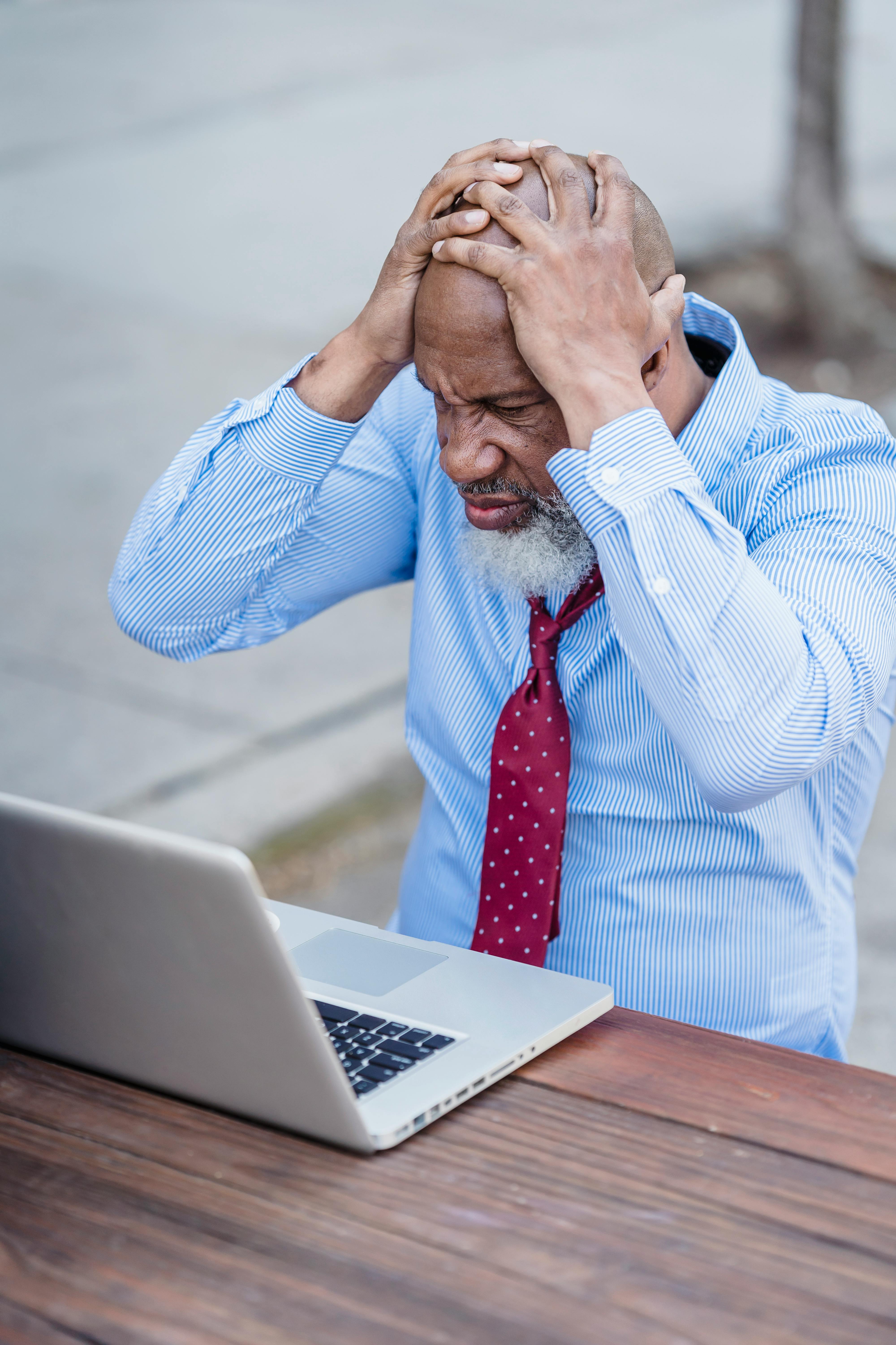 stressed elderly african american man grabbing head