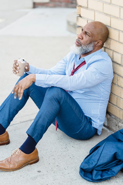 Free Black man relaxing with beer near building wall Stock Photo