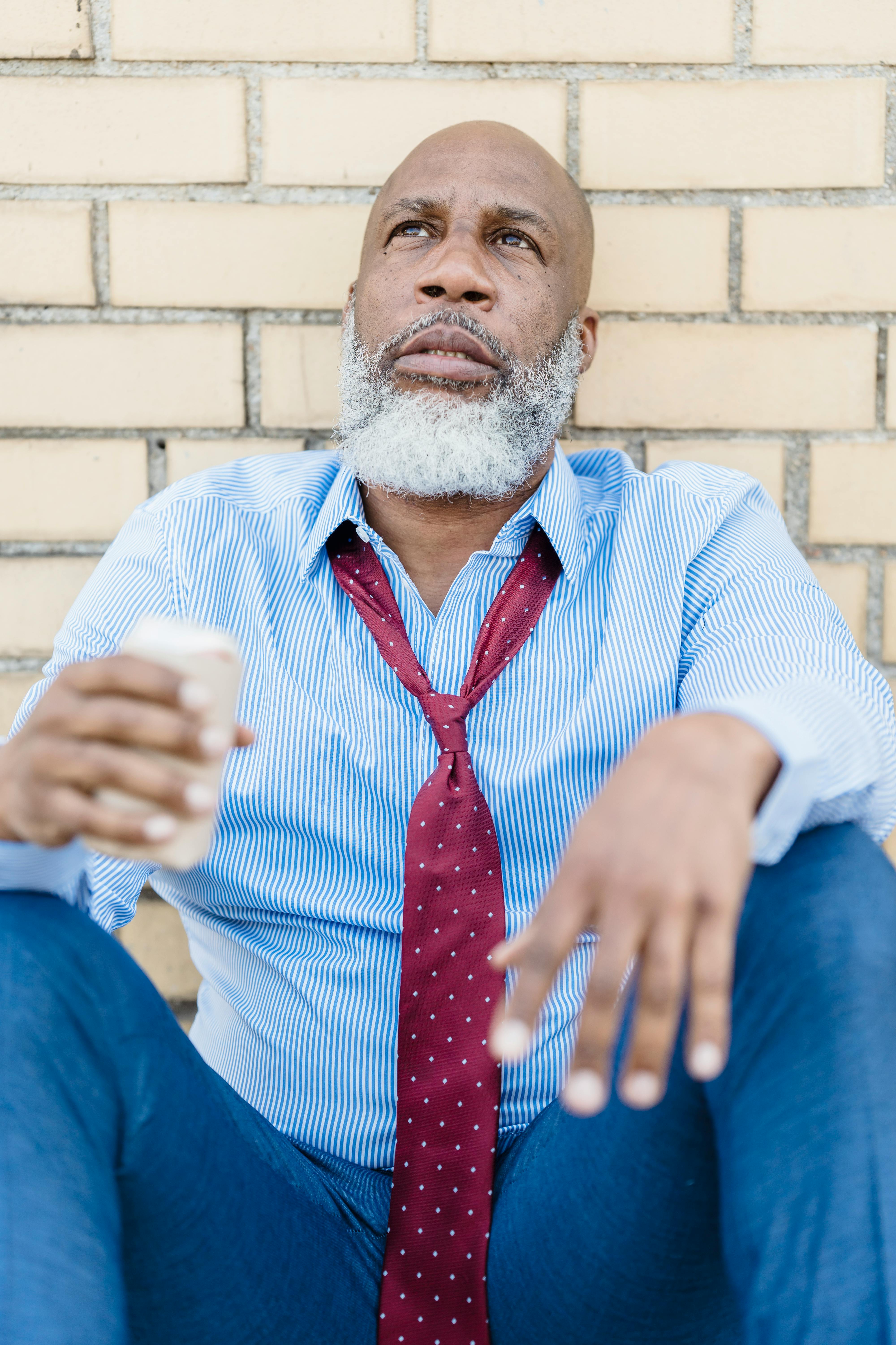 african american man sitting on street with beer can