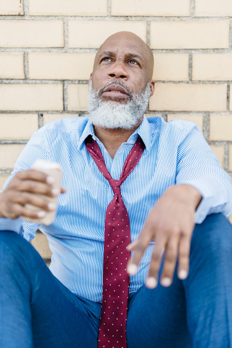 African American Man Sitting On Street With Beer Can