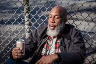 African American homeless man holding beer on street