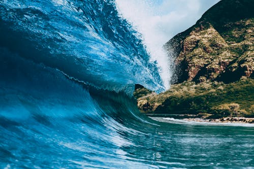Free Powerful turquoise wave of turquoise sea crashing on coast with steep rocky cliff Stock Photo