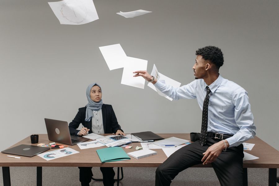 Two colleagues in an office with paperwork in mid-air — photo by Pavel Danilyuk on Pexels