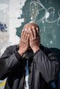 Black man covering face with hands