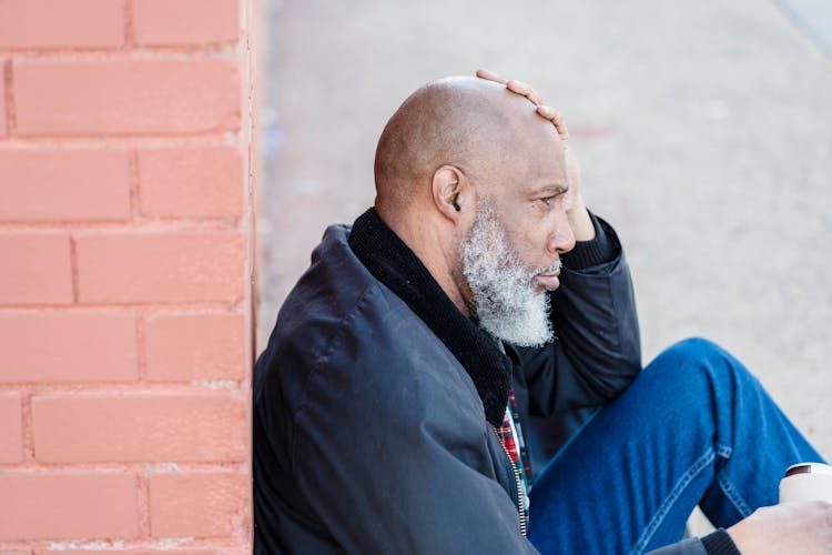 Stressed Old Man Sitting On Ground On Street