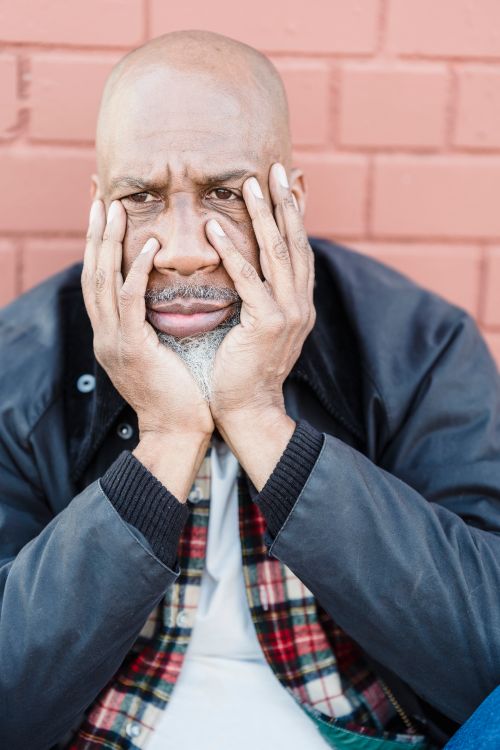 Free A thoughtful portrait of a bald man in a black jacket against a brick wall, conveying deep emotion. Stock Photo