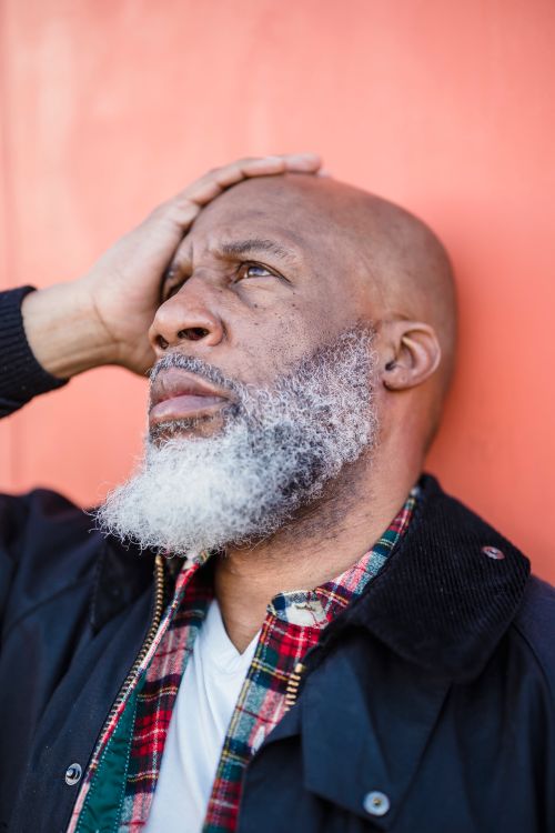 Free Close-up of a thoughtful bald African American man with a white beard against an orange background. Stock Photo