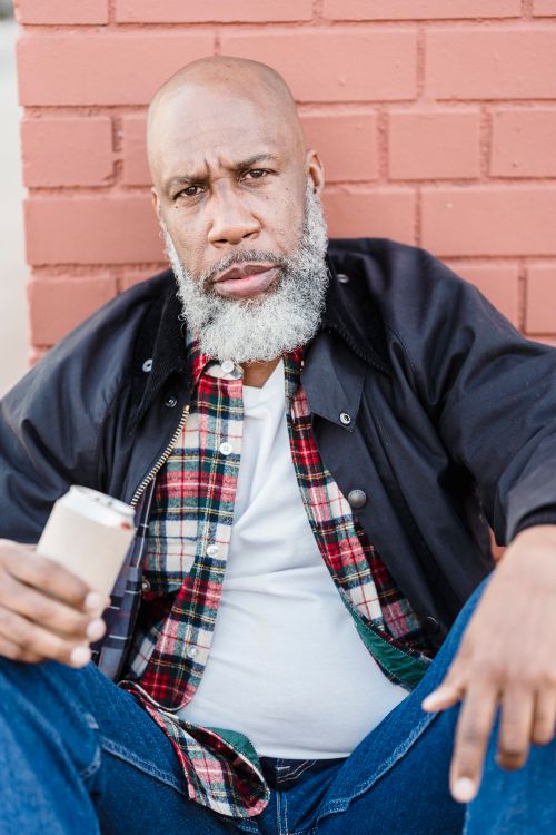 Free Portrait of a mature bearded man in a casual outfit against a brick wall. Stock Photo