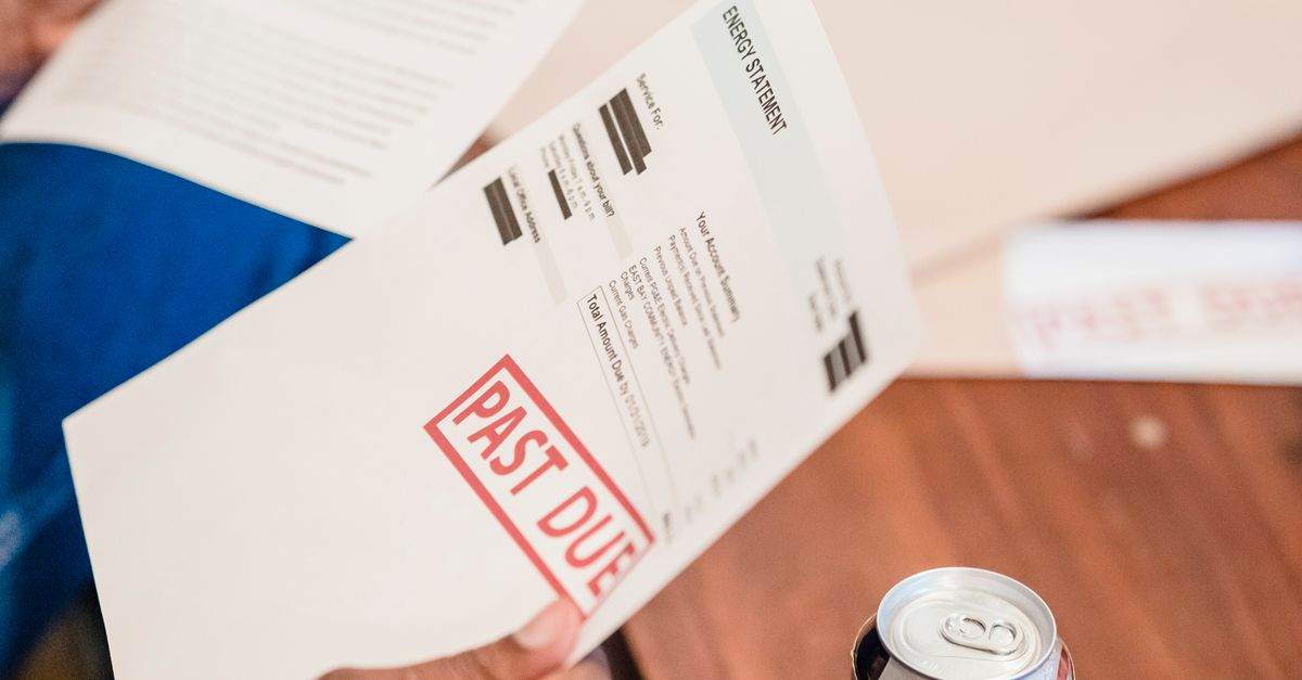 Photo by Nicola Barts Close-up of a man reading past due notices and bankruptcy papers at a table.