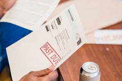 Close-up of a man reading past due notices and bankruptcy papers at a table.