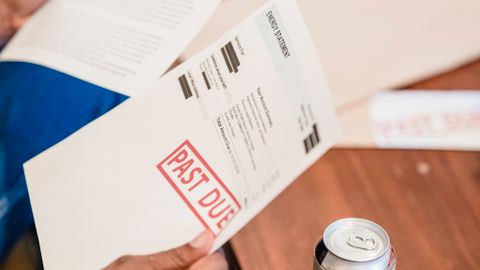 Close-up of a man reading past due notices and bankruptcy papers at a table.