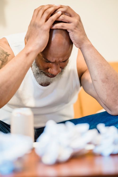 Free Man in distress holding head surrounded by tissues, expressing anxiety. Stock Photo